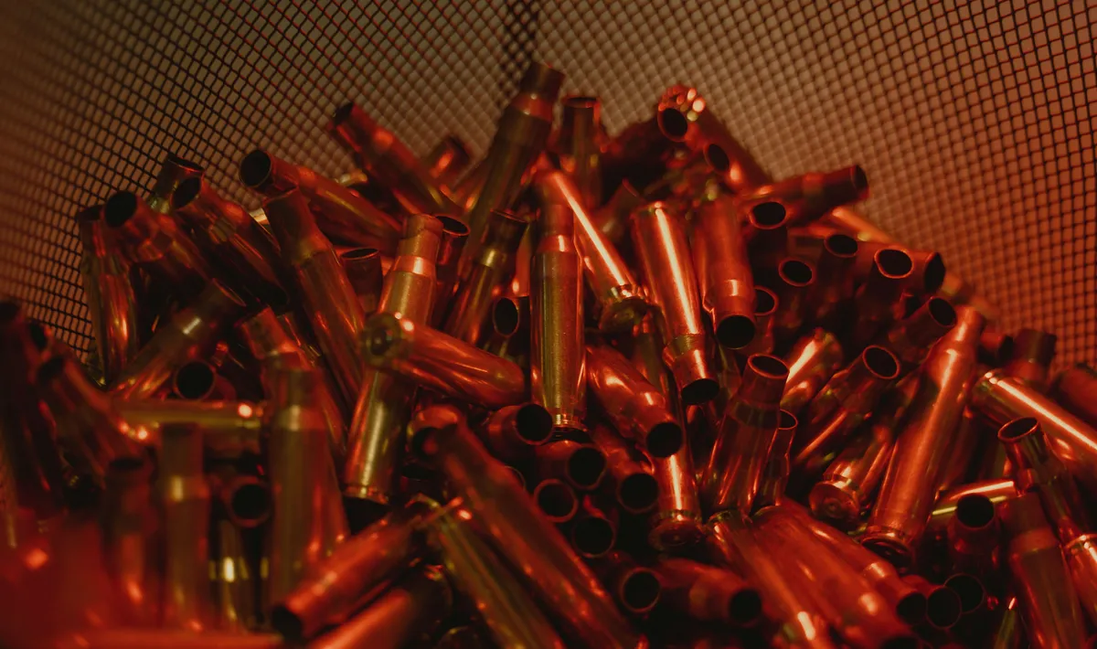 Łuski z amunicji 5.56 leżące w kupce w czerwonym świetle